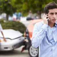Man talking on his phone after suffering a car accident