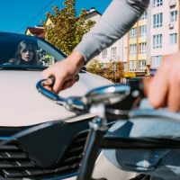 Woman in a car about to hit a bicycle rider