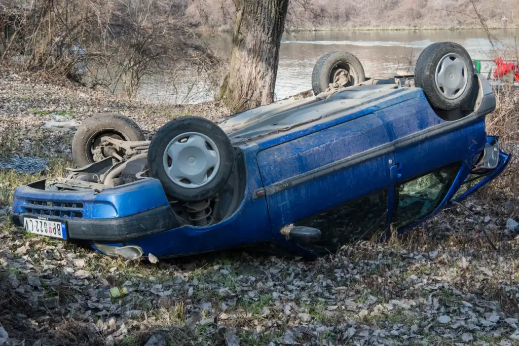 Rollover car accident with a blue vehicle flipped onto its side, illustrating the severity of accidents and the risk of injuries in rollover crashes.