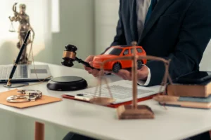 Attorney holding a gavel and a toy car, symbolizing legal representation for uninsured motorist claims and accidents.
