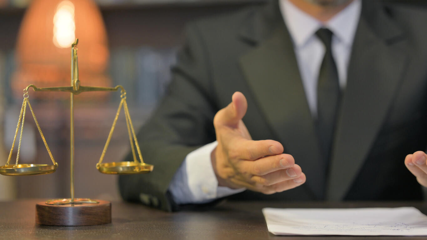 Scale of justice on desk with lawyer, representing a Fremont slip and fall lawyer.