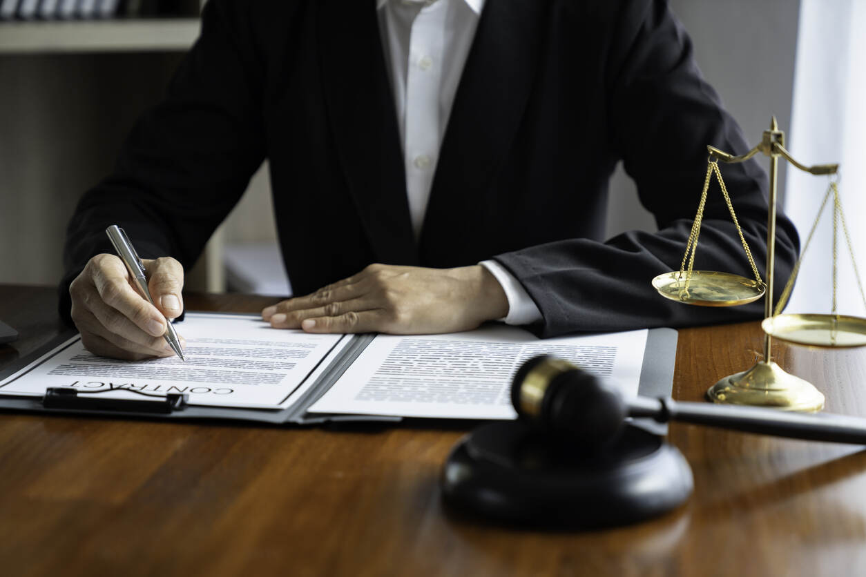 A lawyer reviewing documents, with a gavel and scales of justice on the table.