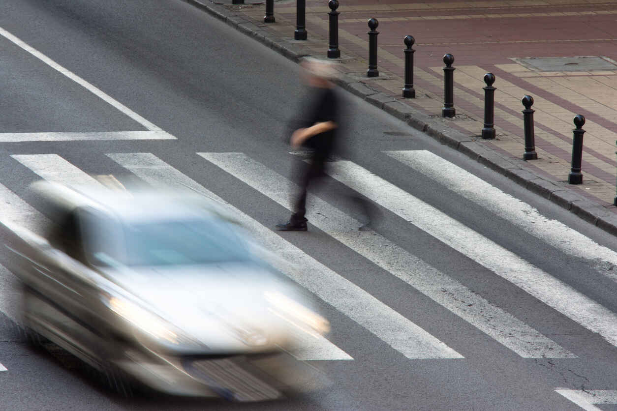 Pedestrian crossing urban street with blurred car and crosswalk, symbolizing a pedestrian accident in San Jose.