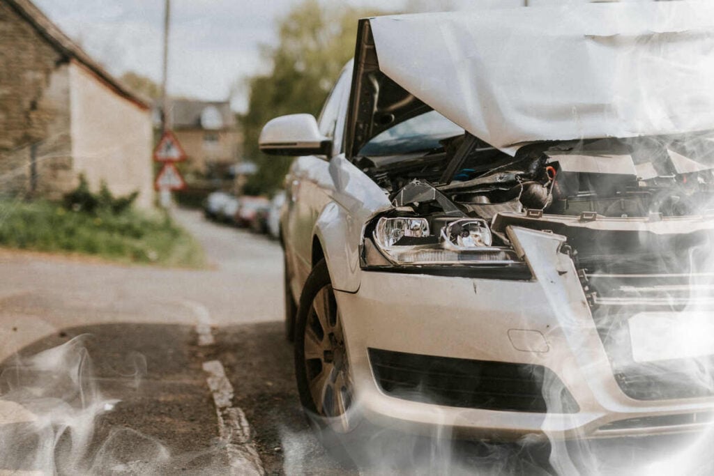 Damaged rental car with crumpled hood and smoke after an accident, for a San Jose rental car accident lawyer