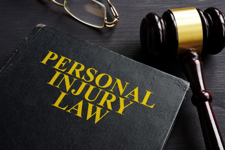 Personal injury law book beside a judge's gavel and reading glasses